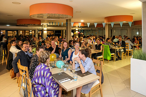 Various people sit at restaurant tables. They are talking and laughing.  © Image: Jorge Gomes