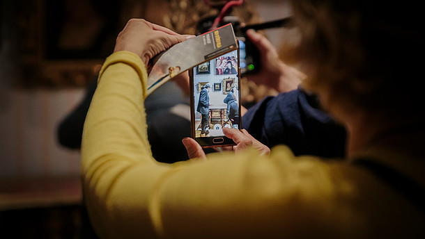  A person is taking a photo of the exhibition display with their smartphone