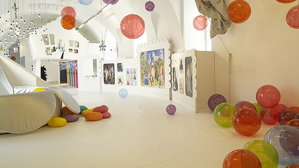 Empty spacious and white room filled with plastic see-through balls. The balls are scattered around the room on the floor, on the walls and attached to the ceiling.   © ZOOM Kindermuseum, Image: Alexandra Eizinger