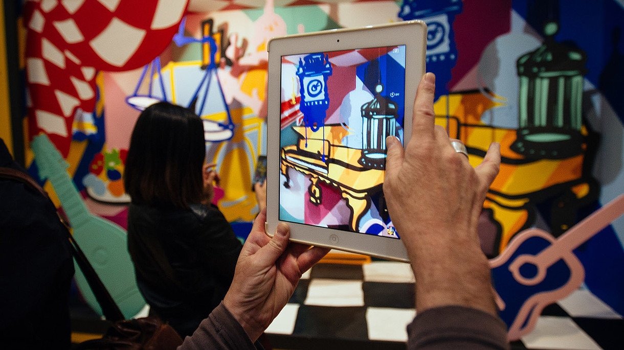 © Image: Courtesy Pimlico Project In this photograph a person takes a photo of a colourful and abstract installation using a tablet. The photo shows only their hands.