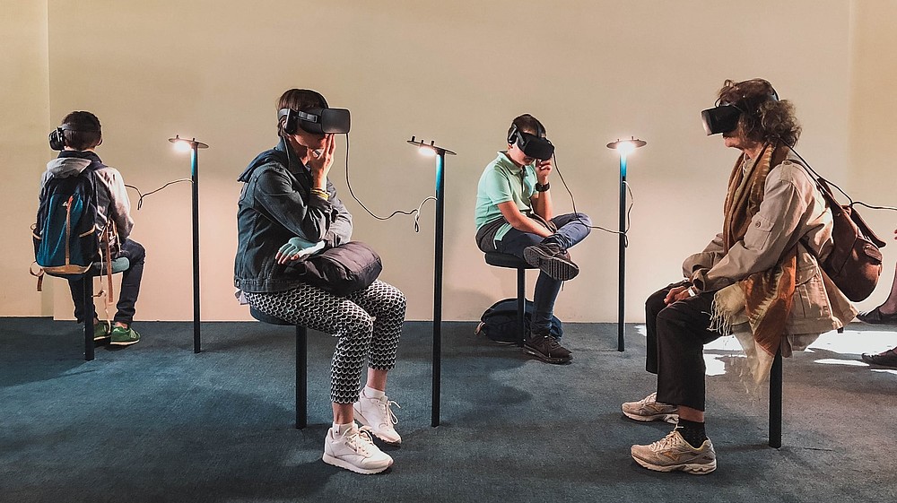 Four people are sitting in a gallery space. All four are wearing goggles and headphones and they are experiencing some kind of virtual reality art.  © Image: Lucrezia Carnelos