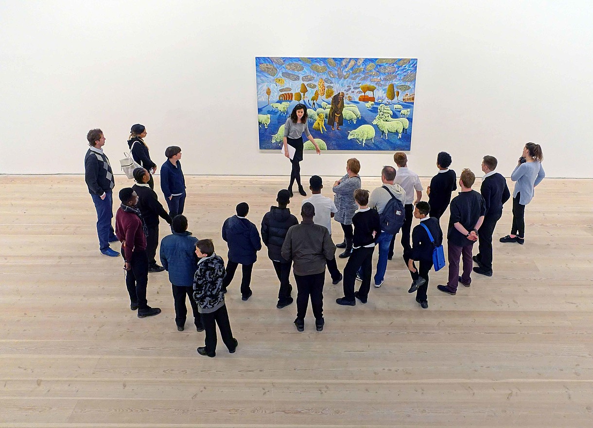 © Jeffrey Blackler / Alamy Stock Foto A group of people stand in front of a modern painting together with a museum educator. The image is photographed from bird perspective.