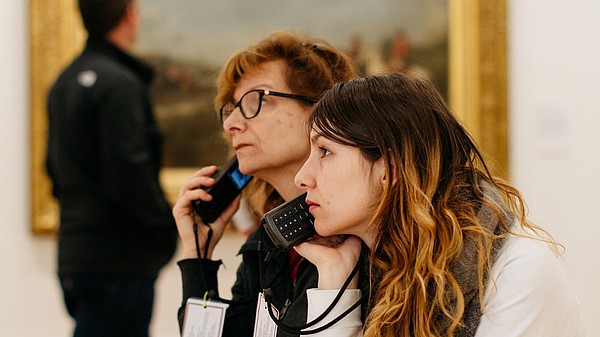 Two people listening to an audio guide