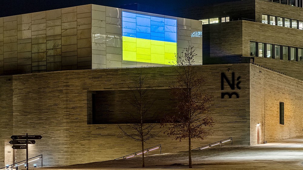 The Ukrainian flag is projected on the wall of a modern building.  