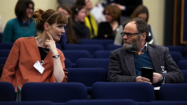  Photo of two people talking in a lecture hall.