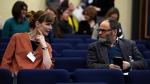  Photo of two people talking in a lecture hall.