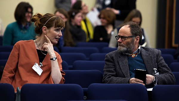 Photo of two people talking in a lecture hall.