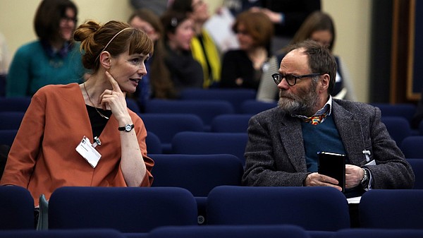 Photo of two people talking in a lecture hall.