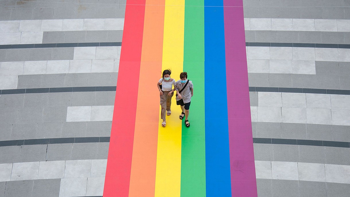 © SOPA Images Limited / Alamy Stock Foto Two people, photogrtaphed from bird perspective, walk over a huge LGBTQ flat that has been attached to the floor.