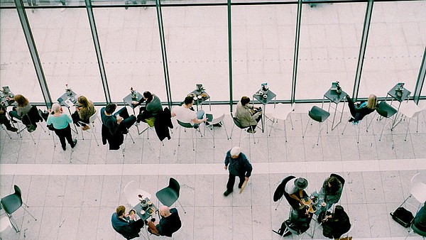 Bird perspective of a cafe with big windows. People are sitting down and walking around.