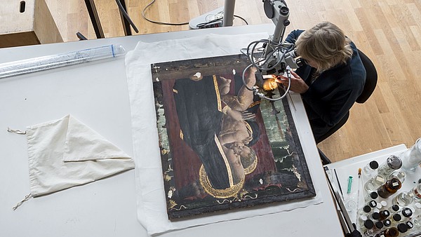 Bird perspective of someone doing restoration work on an icon painting. 