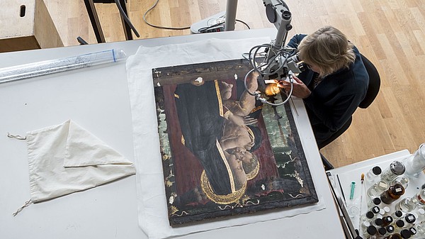 Bird perspective of someone doing restoration work on an icon painting. 