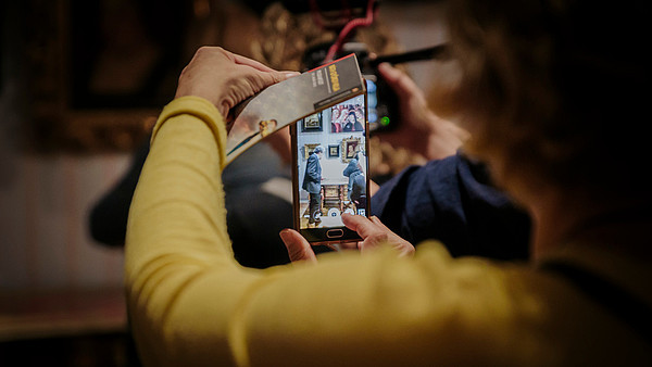 A person is taking a photo of the exhibition display with their smartphone