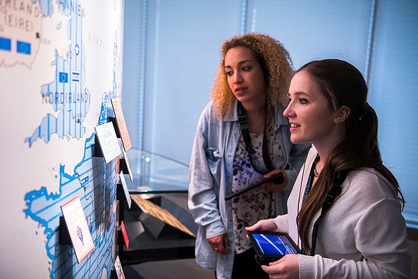 Two people use a tablet to engage with an interactive art piece.
