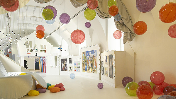 Empty spacious and white room filled with plastic see-through balls. The balls are scattered around the room on the floor, on the walls and attached to the ceiling. 