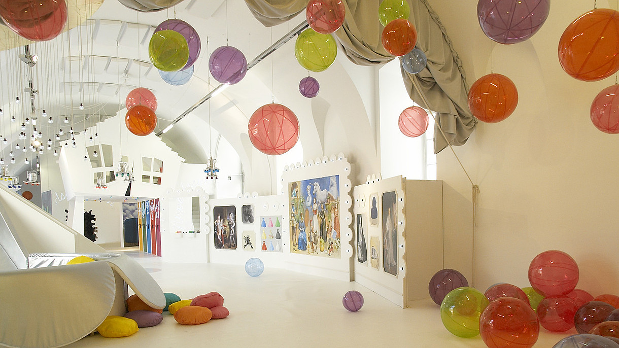 © ZOOM Kindermuseum, Image: Alexandra Eizinger Empty spacious and white room filled with plastic see-through balls. The balls are scattered around the room on the floor, on the walls and attached to the ceiling. 