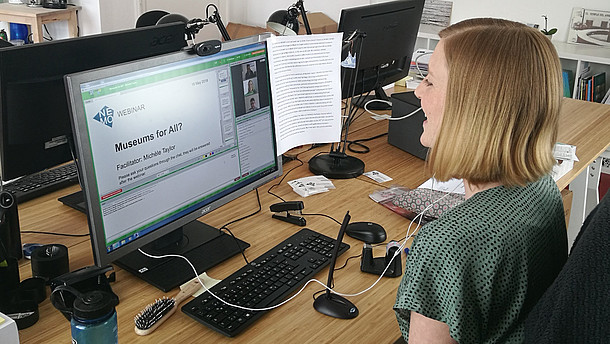 Person sitting in front of a computer preparing a webinar.   
