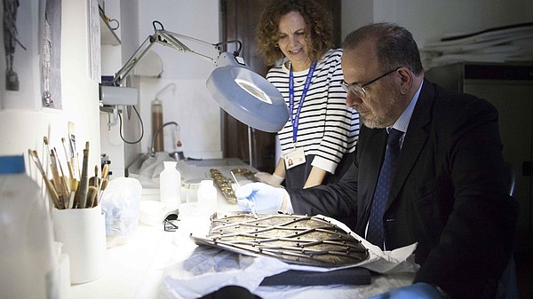 Man restoring an ancient piece of art with the guidance of a restaurator