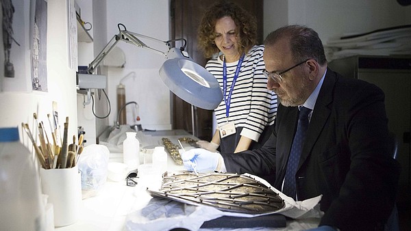 Man restoring an ancient piece of art with the guidance of a restaurator