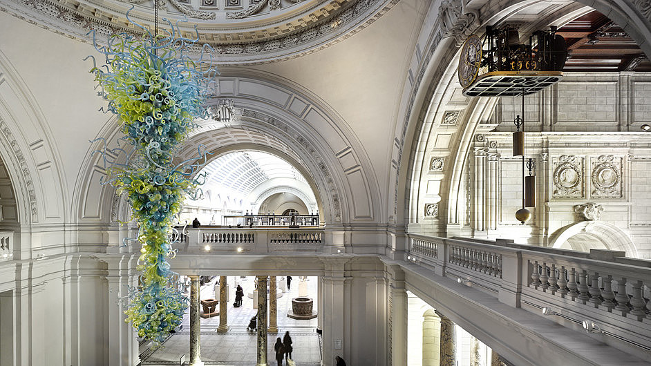 Modern glass sculpture in green and blue hanging from the ceiling of a classic building.  © Victoria and Albert Museum, Image: James Medcraft