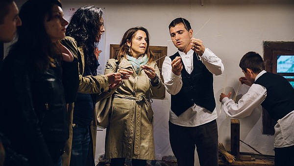 A person is demonstrating a traditional craft to a group of people. 
