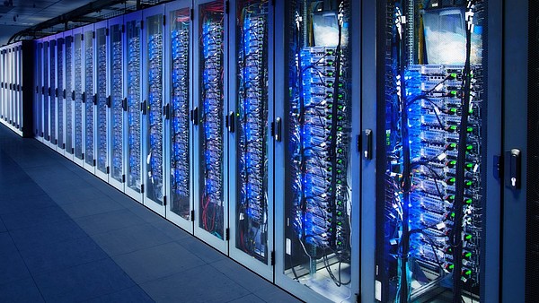 A row of cabinets is filled with server racks in a data center.