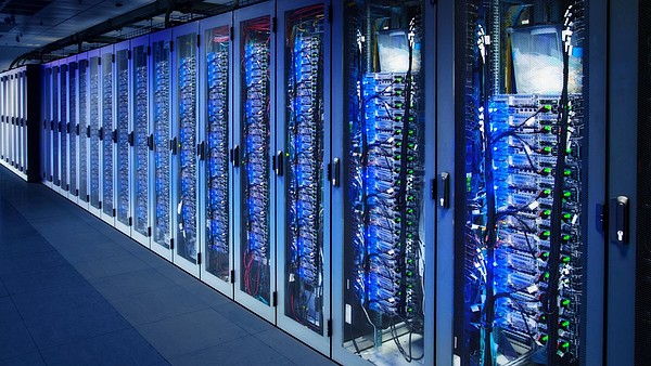 A row of cabinets is filled with server racks in a data center.