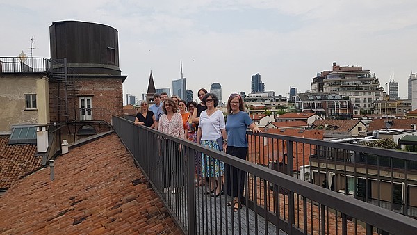 A group of people standing on a rooftop pathway.
