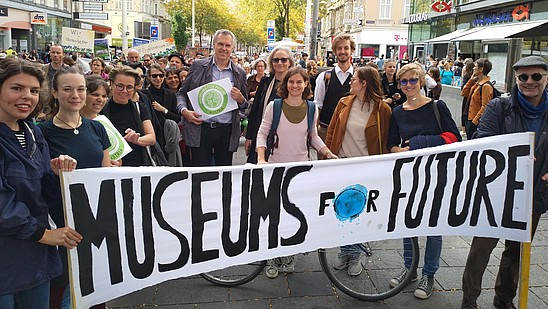 Group of people at a demonstration for the environment carrying a banner that says "Museums for Future"