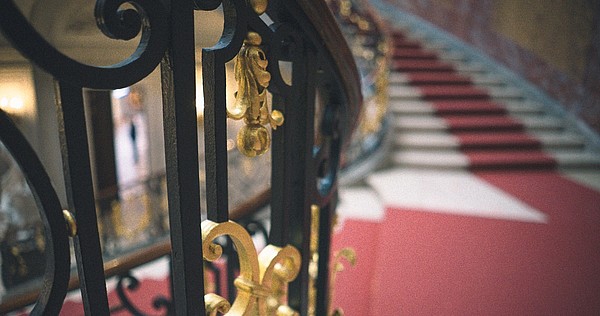 Detail of an iron handrail with view of the stairwell in the back.