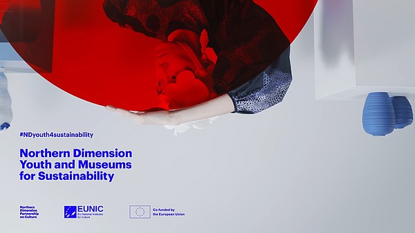 This is an upside down photograph of a person holding a red circle made from acrylic glass. Through the red glass we can see their face. Added to the picture is blue text which announces the Northern Dimension programme Youth and Museums for Sustainability.