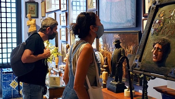 Two people wearing nose and mouth covering masks are looking at art hanging on the wall.  © Arxiu Fotogràfic del Consorci del Patrimoni de Sitges