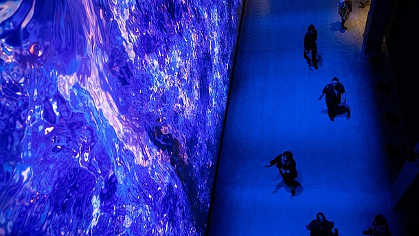 Photograph taken from bird perspective of people standing in front of an art installation. The installation bathes the room in blue light.  © Image: Lassi Haekkine-City of Lahti