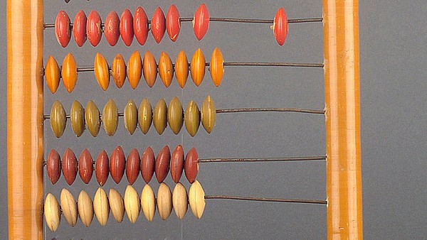 This image depicts a wooden slide rule against a grey background.