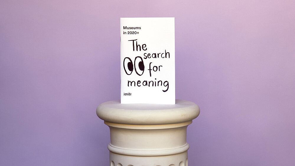  A card is placed on an antique socket, set before a lilac background. The white card reads "The search for meaning". Next to the writing two eyes are drawn in cartoonish style.
