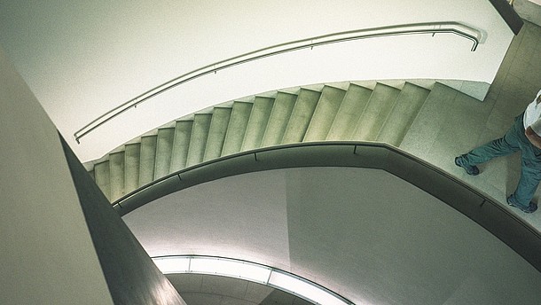  Abstract view of a modern stairwell from above. To the right a person is shown walking out of the picture frame.