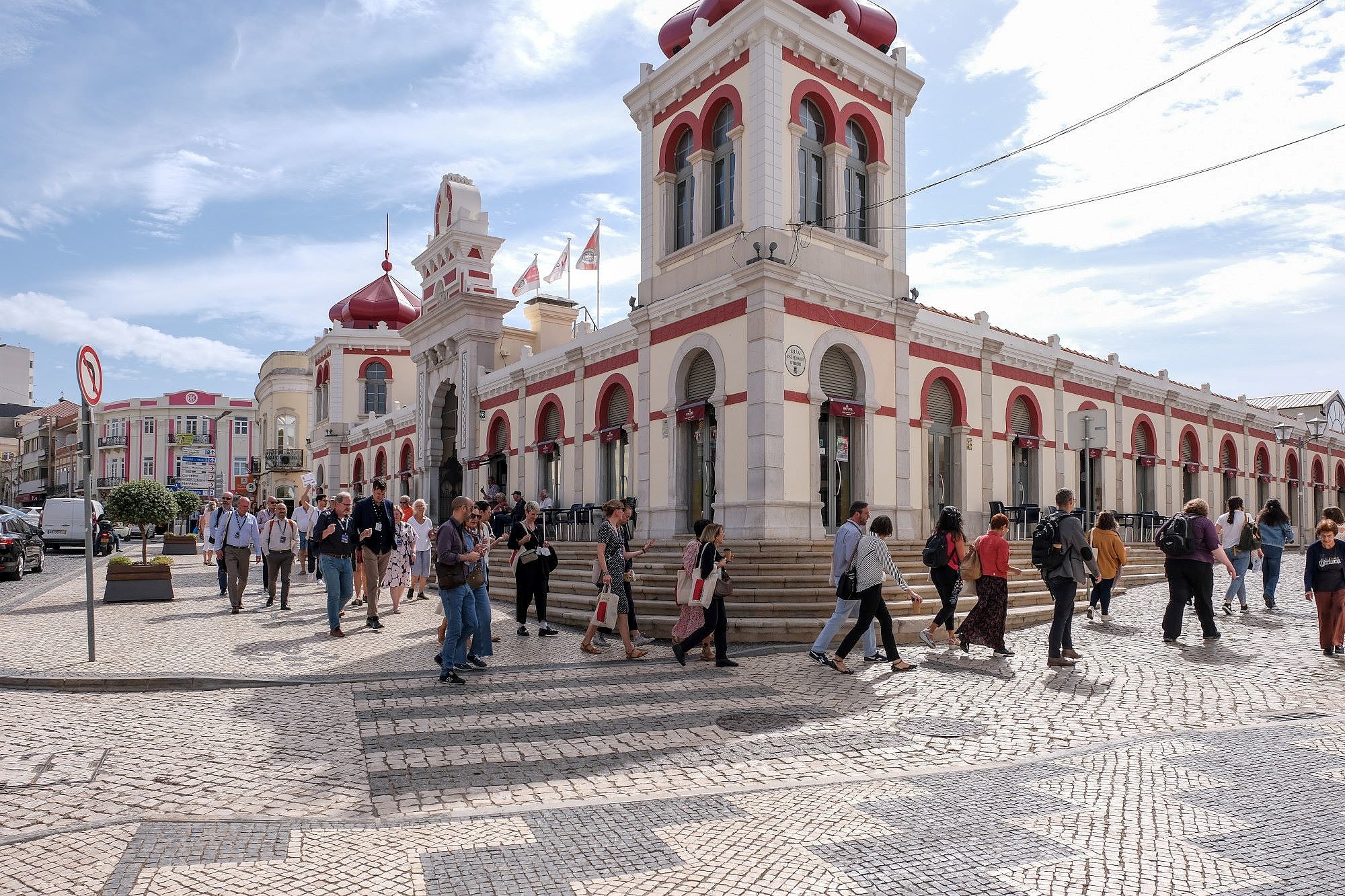 People are walking and talking to each other in small groups. In the background is a historic building.  © Image: Jorge Gomes