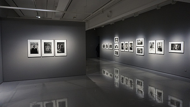  Grey gallery space with shiny floors that reflects the photos hung on the walls.
