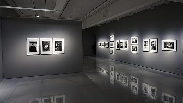 Grey gallery space with shiny floors that reflects the photos hung on the walls.