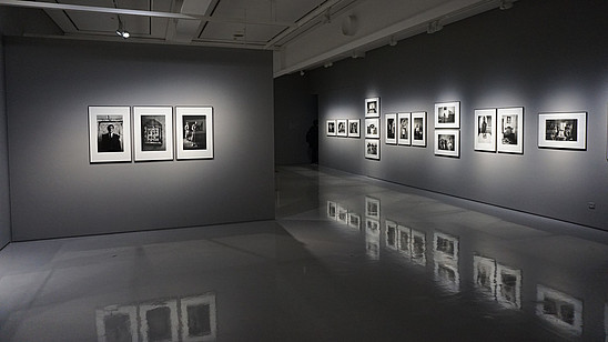 Grey gallery space with shiny floors that reflects the photos hung on the walls.