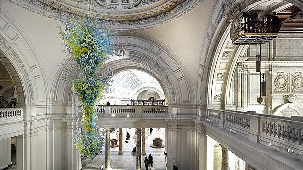 Modern glass art piece hanging from the ceiling of a classic building.
