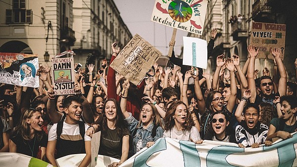 Young people are shouting and holding banners during a climate protest.