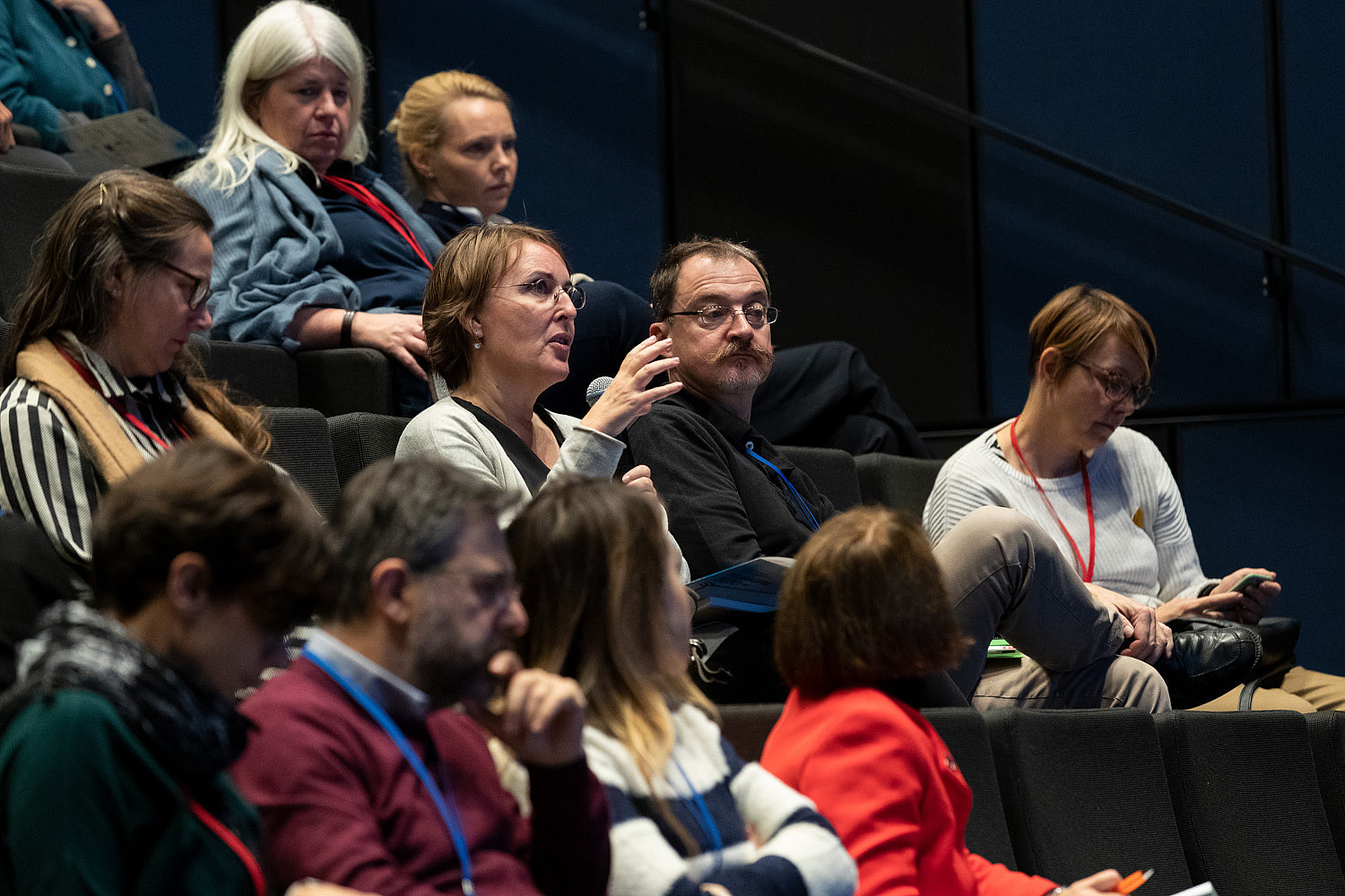 A person sitting in an audience uses a microphone to ask a question.   © Image: Berta Jänes